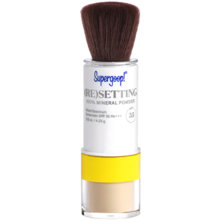 tube of supergoop resetting mineral powder spf with brush out on a white background
